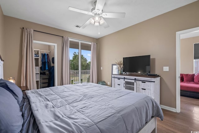bedroom featuring wood finished floors, access to exterior, a spacious closet, baseboards, and a closet