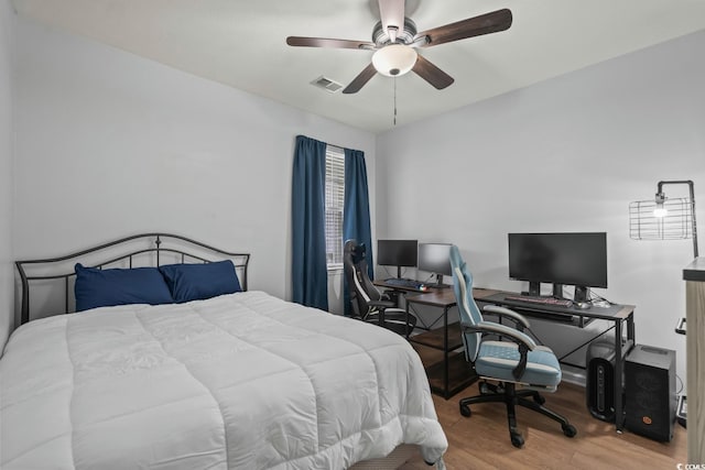 bedroom featuring wood finished floors, an office area, and a ceiling fan