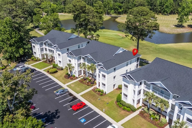 drone / aerial view of a large body of water, apartment complex, and a golf club