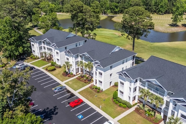 bird's eye view of a nearby body of water, apartment complex / building, and a local golf course