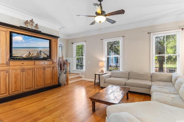 living area with crown molding, light wood-style floors, a ceiling fan, stairs, and baseboards