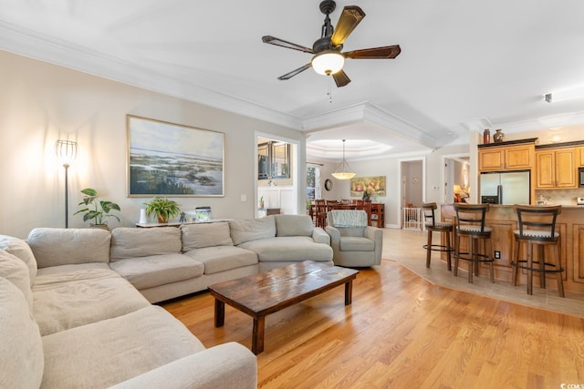 living room featuring ornamental molding, a ceiling fan, and light wood-type flooring