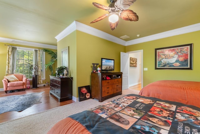 bedroom featuring crown molding, wood finished floors, baseboards, and ceiling fan