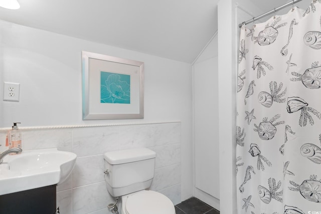 full bathroom featuring toilet, tile walls, lofted ceiling, vanity, and tile patterned floors