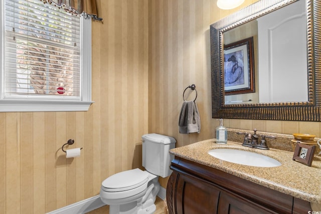 half bath featuring toilet, baseboards, and vanity