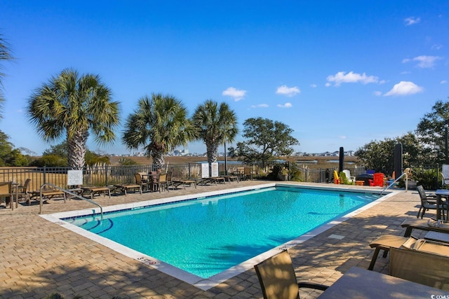 community pool with a patio and fence