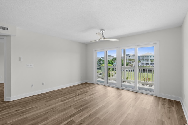 spare room with ceiling fan, wood finished floors, baseboards, and a textured ceiling