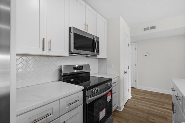 kitchen featuring appliances with stainless steel finishes, tasteful backsplash, dark wood-style flooring, and baseboards