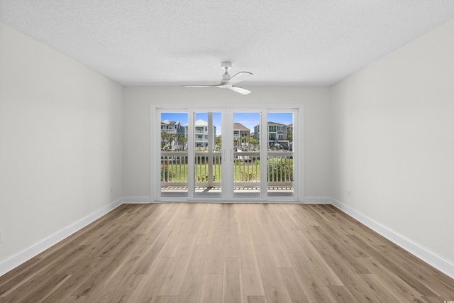 empty room featuring ceiling fan, wood finished floors, baseboards, and a textured ceiling