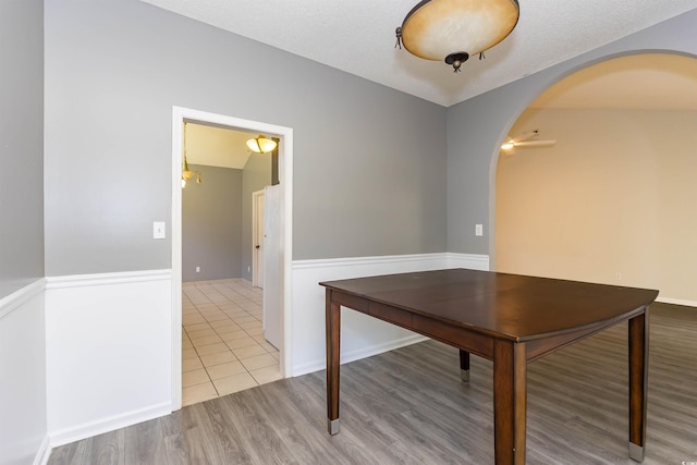 unfurnished office featuring arched walkways, wood finished floors, and ceiling fan