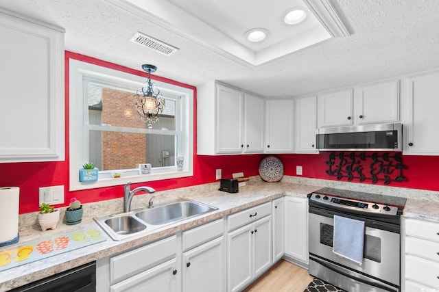 kitchen featuring appliances with stainless steel finishes, a sink, white cabinetry, a textured ceiling, and light countertops