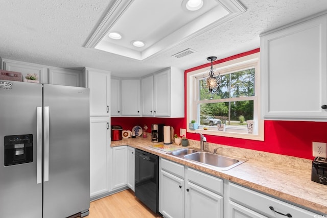 kitchen with stainless steel fridge, black dishwasher, a textured ceiling, a sink, and light countertops