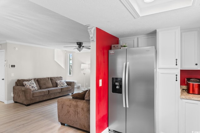 kitchen featuring stainless steel fridge, light wood-type flooring, white cabinetry, a ceiling fan, and ornamental molding