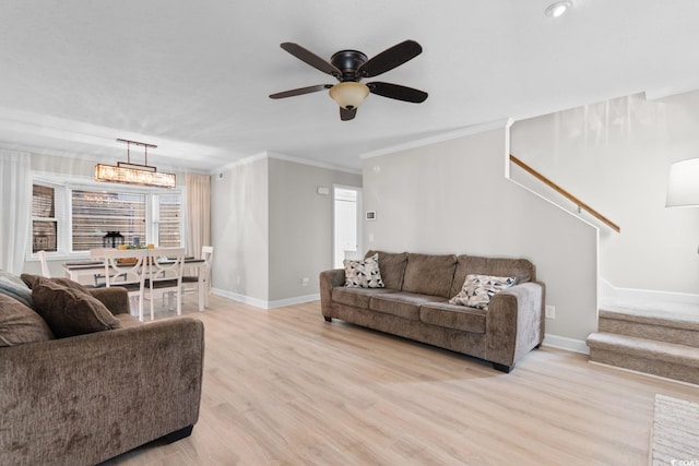 living room with stairs, baseboards, light wood-type flooring, a ceiling fan, and ornamental molding