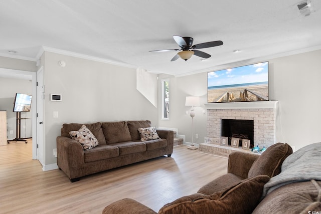 living area with light wood-style floors, a ceiling fan, crown molding, baseboards, and a fireplace