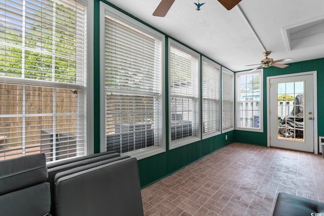 unfurnished sunroom with a ceiling fan and brick patterned flooring