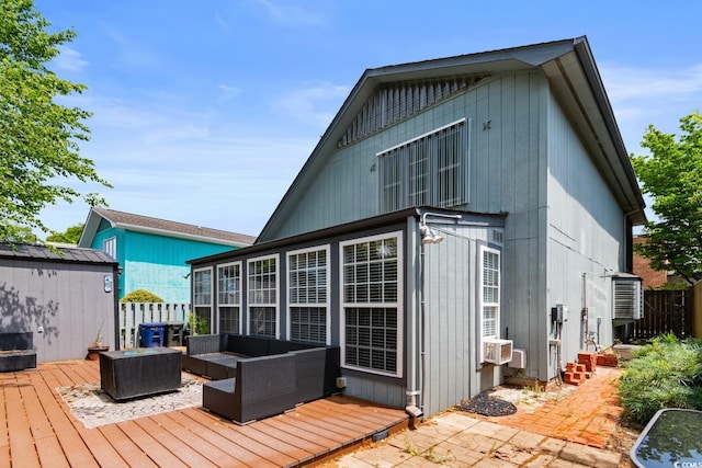 back of house featuring a wooden deck, an outdoor living space, fence, a storage unit, and an outdoor structure