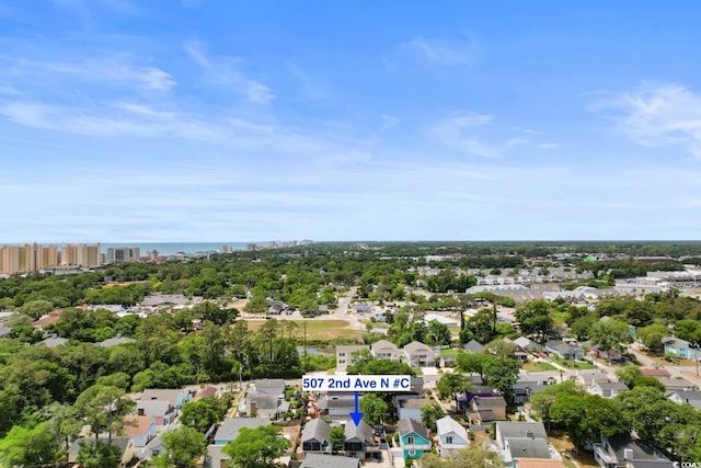 view of property location featuring a tree filled landscape and nearby suburban area