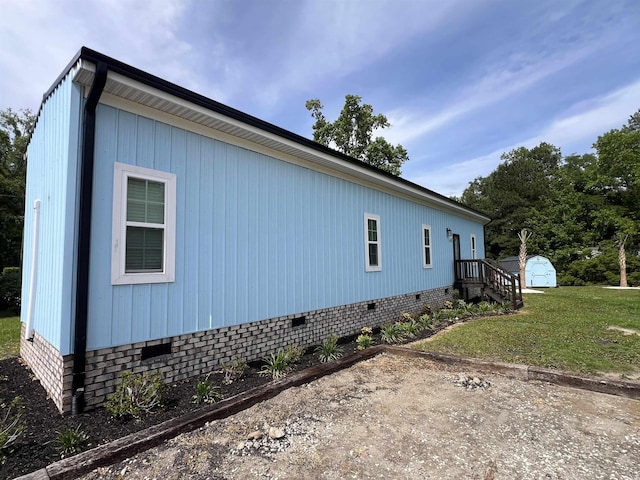 view of side of property featuring crawl space, a shed, an outbuilding, and a lawn