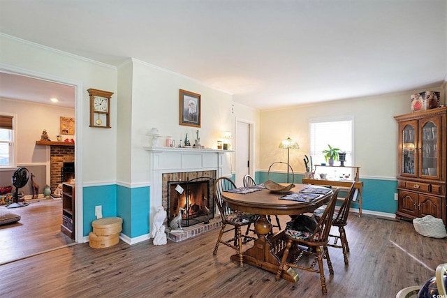 dining area featuring a fireplace, healthy amount of natural light, wood finished floors, and ornamental molding