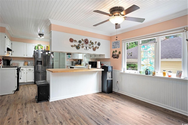 kitchen with fridge with ice dispenser, gas range, a peninsula, crown molding, and wood finished floors
