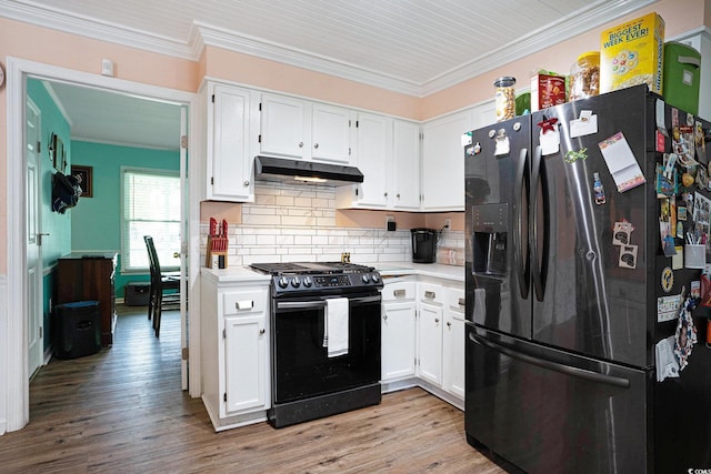 kitchen with black refrigerator with ice dispenser, range with gas stovetop, under cabinet range hood, crown molding, and light countertops
