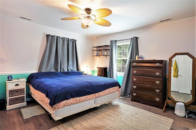 bedroom with wood finished floors, crown molding, and ceiling fan