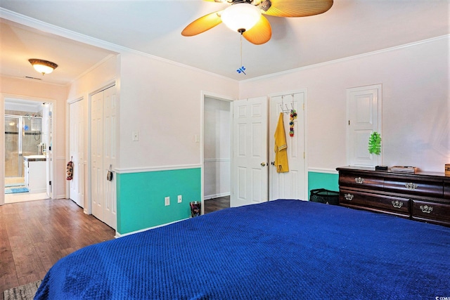 bedroom featuring crown molding, multiple closets, wood finished floors, ensuite bath, and a ceiling fan