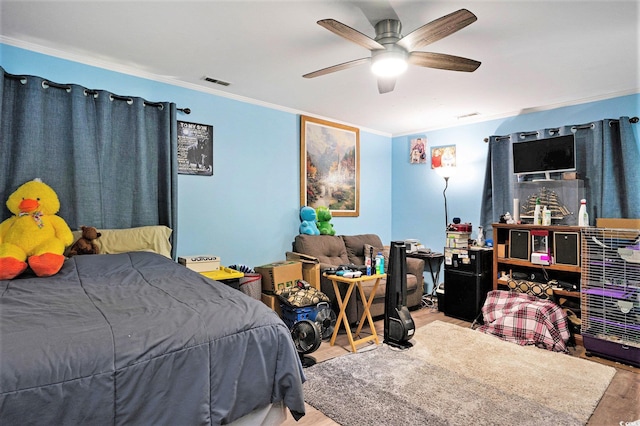bedroom with ornamental molding, wood finished floors, and a ceiling fan