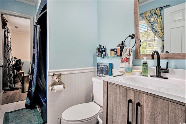 bathroom with toilet, a wainscoted wall, crown molding, vanity, and tile patterned floors