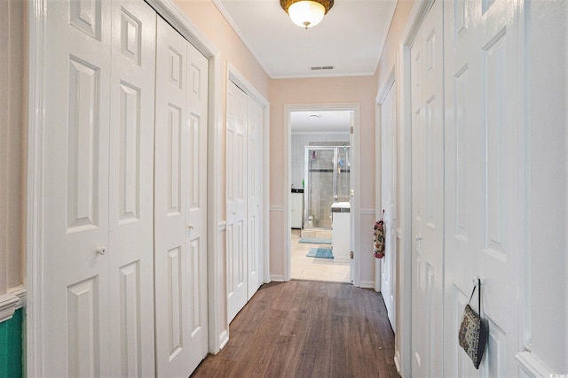 corridor featuring dark wood finished floors, crown molding, and baseboards