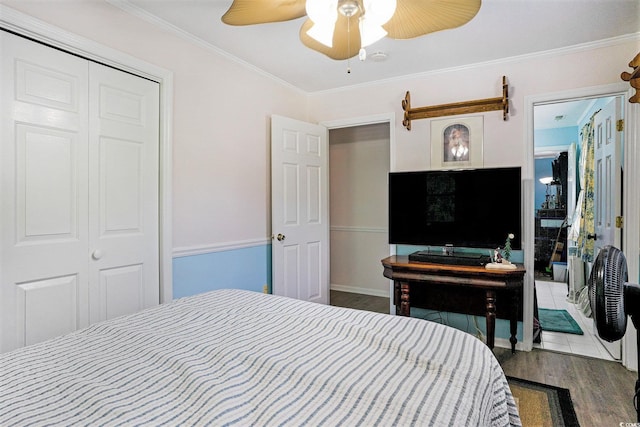 bedroom featuring wood finished floors, ornamental molding, ceiling fan, and a closet