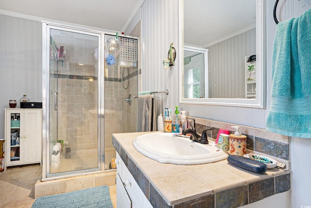 full bath featuring crown molding, a stall shower, vanity, and wallpapered walls