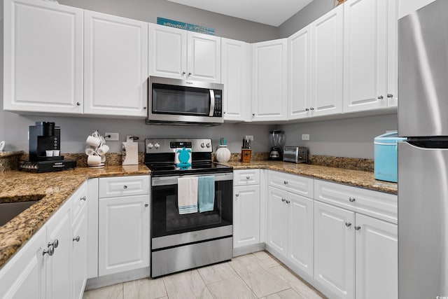 kitchen with appliances with stainless steel finishes, light marble finish flooring, white cabinetry, and light stone counters