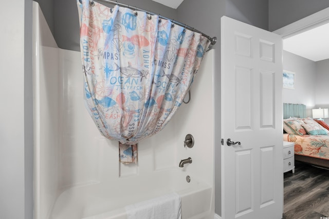 ensuite bathroom featuring wood finished floors and shower / bath combo with shower curtain