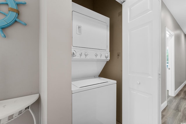 laundry area featuring estacked washer and dryer, light wood-type flooring, and baseboards