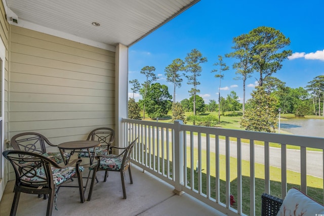 balcony featuring a water view and view of scattered trees