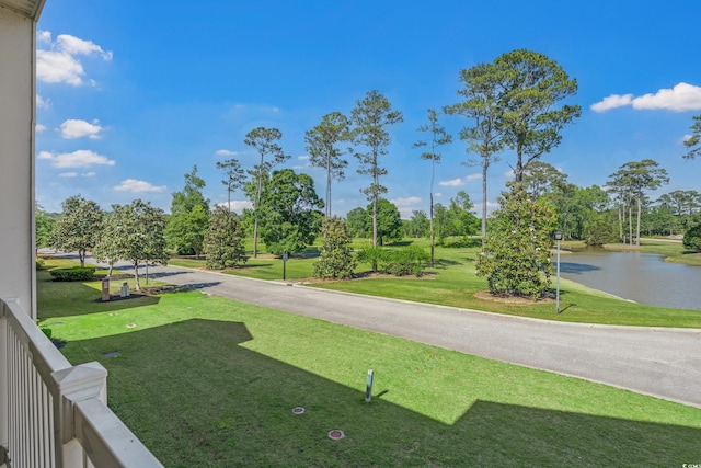 view of grassy yard featuring a water view and view of wooded area