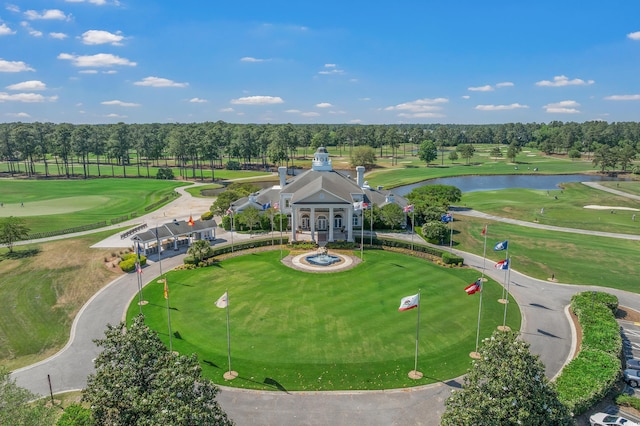 drone / aerial view of a nearby body of water, a golf course, and a tree filled landscape