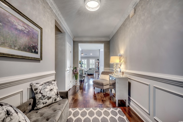 corridor featuring wood finished floors, ornamental molding, a wainscoted wall, and a decorative wall
