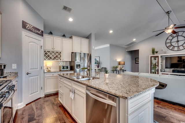 kitchen featuring stainless steel appliances, open floor plan, a sink, vaulted ceiling, and ceiling fan