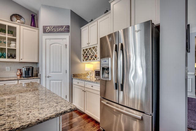 kitchen featuring stainless steel fridge, decorative backsplash, dark wood-style floors, white cabinets, and vaulted ceiling