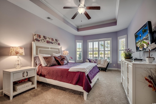 bedroom with a raised ceiling, light colored carpet, crown molding, baseboards, and a ceiling fan