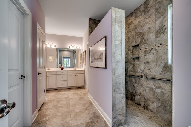 bathroom with a walk in shower, double vanity, and baseboards