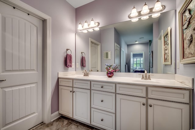 bathroom with double vanity, connected bathroom, and baseboards