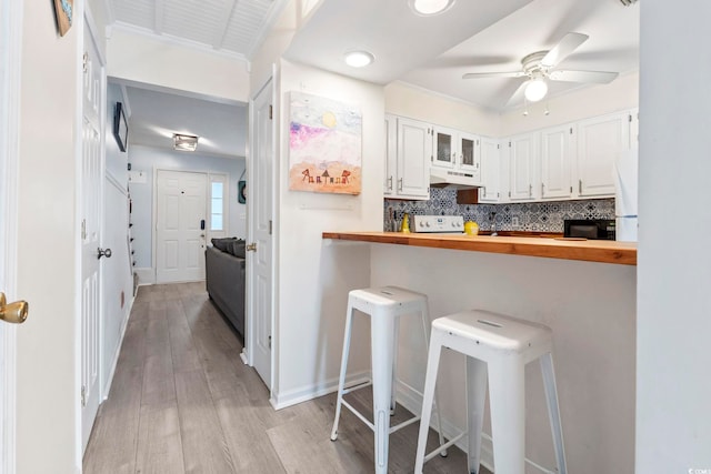 3008 Church St Unit D3, Myrtle Beach, SC 29577 - kitchen featuring under cabinet range hood, butcher block countertops, a ceiling fan, a kitchen breakfast bar, and white cabinetry