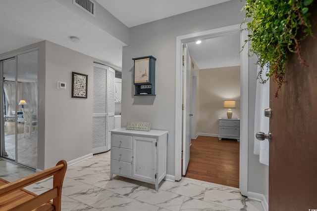 hall featuring light marble finish floors and baseboards