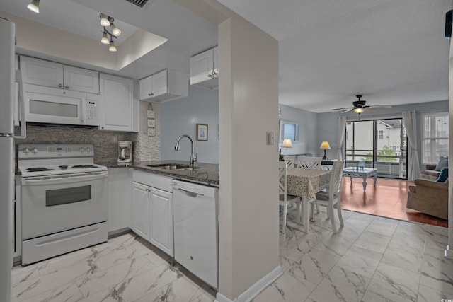 kitchen with white appliances, a sink, light marble finish floors, dark stone countertops, and open floor plan