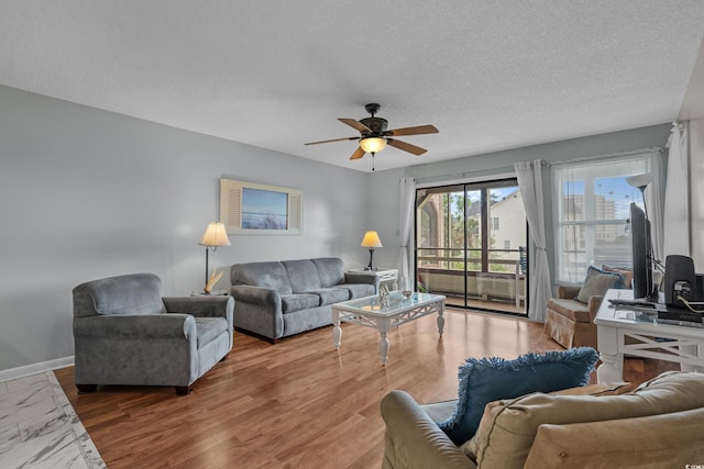 living room featuring ceiling fan, a textured ceiling, and baseboards