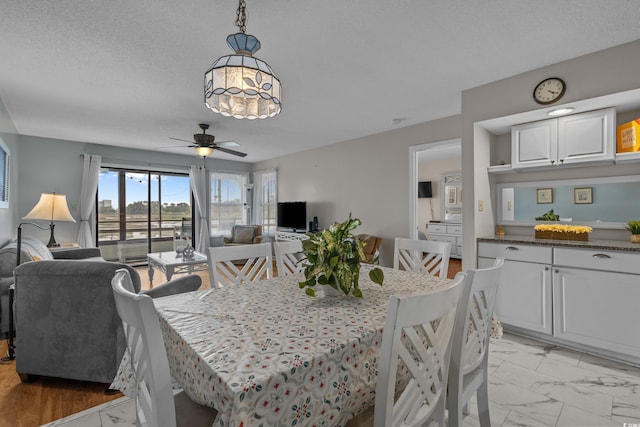 dining room featuring ceiling fan and light marble finish floors